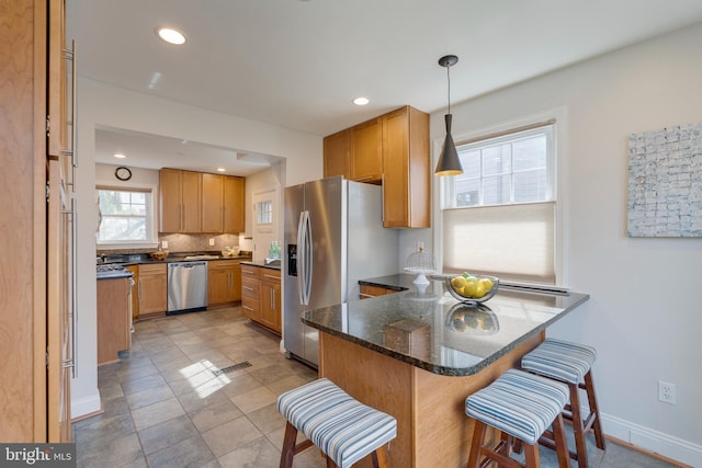 kitchen with tasteful backsplash, baseboards, appliances with stainless steel finishes, a breakfast bar area, and a peninsula