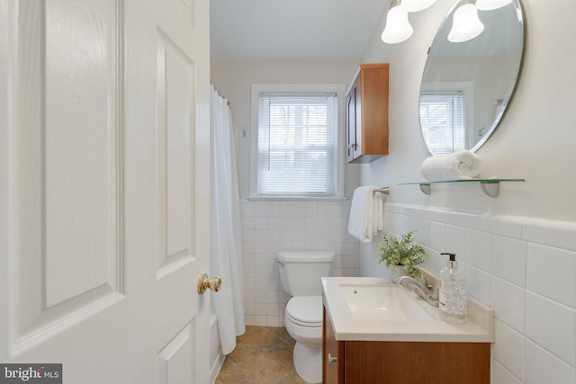 full bathroom with tile walls, toilet, wainscoting, vanity, and tile patterned floors