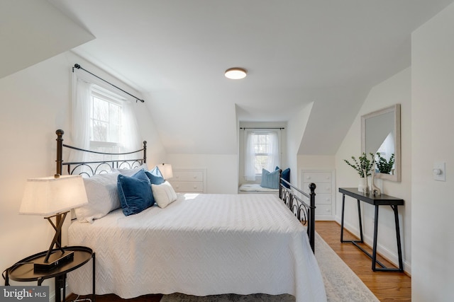 bedroom featuring vaulted ceiling, baseboards, and wood finished floors