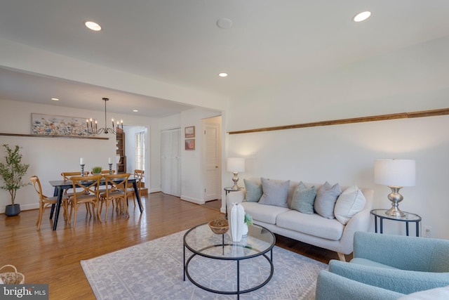 living area featuring a chandelier, recessed lighting, baseboards, and wood finished floors