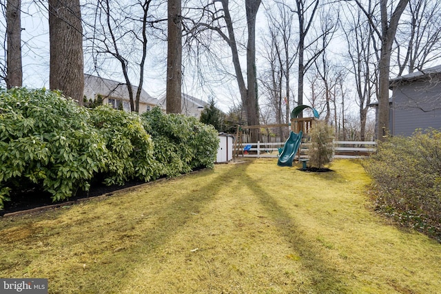 view of yard featuring a playground, fence, an outdoor structure, and a storage shed