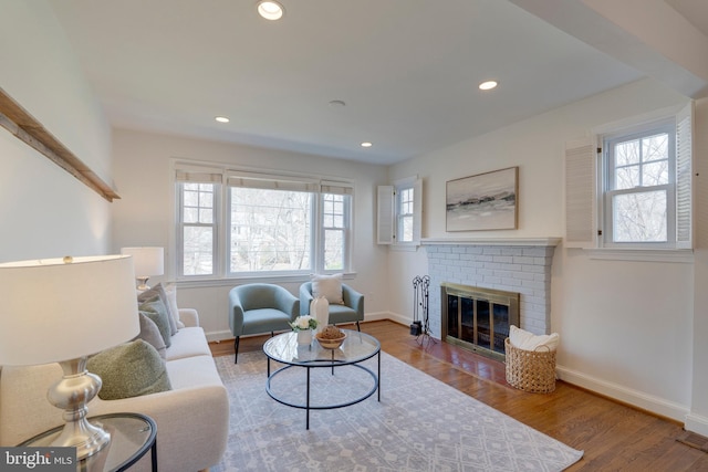 living room with recessed lighting, a brick fireplace, plenty of natural light, and wood finished floors