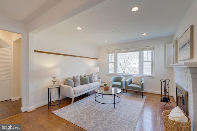 living area with a brick fireplace, wood-type flooring, baseboards, and recessed lighting