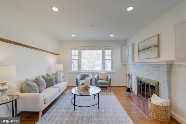 living area with a brick fireplace, baseboards, wood finished floors, and recessed lighting