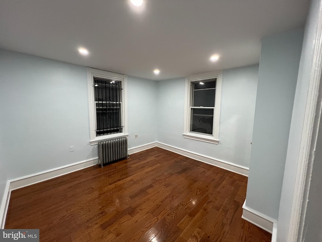 unfurnished room with radiator heating unit and dark hardwood / wood-style flooring