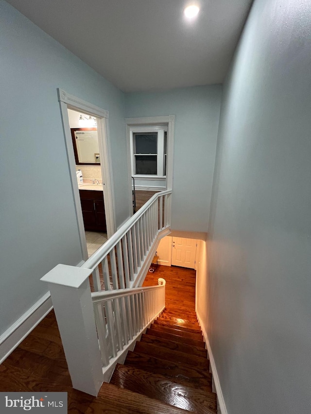 staircase featuring hardwood / wood-style floors and sink