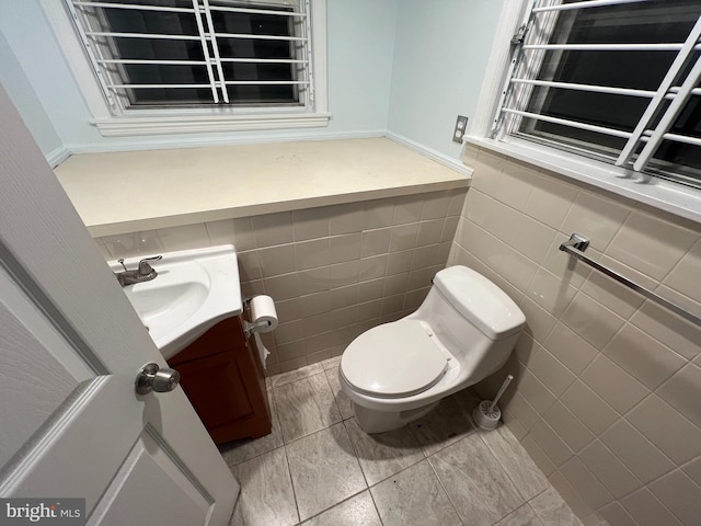 bathroom featuring tile walls, vanity, toilet, and tile patterned flooring