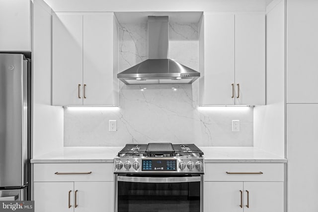 kitchen featuring stainless steel appliances, backsplash, white cabinets, and wall chimney range hood