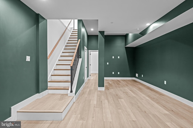 below grade area featuring stairs, baseboards, wood finished floors, and recessed lighting