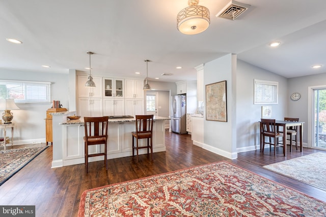 kitchen with dark hardwood / wood-style flooring, decorative light fixtures, white cabinets, stainless steel refrigerator, and lofted ceiling