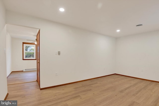 spare room with a baseboard heating unit, ceiling fan, and light hardwood / wood-style flooring