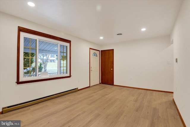 empty room with a baseboard radiator and light hardwood / wood-style floors