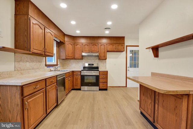 kitchen with sink, tasteful backsplash, light hardwood / wood-style flooring, kitchen peninsula, and stainless steel appliances