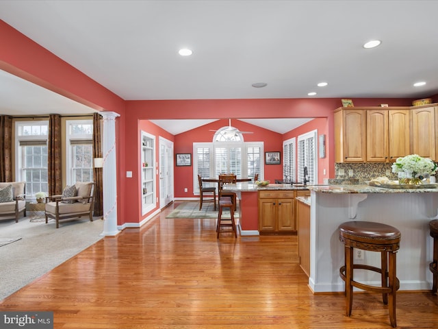 kitchen with lofted ceiling, kitchen peninsula, a kitchen bar, and a healthy amount of sunlight