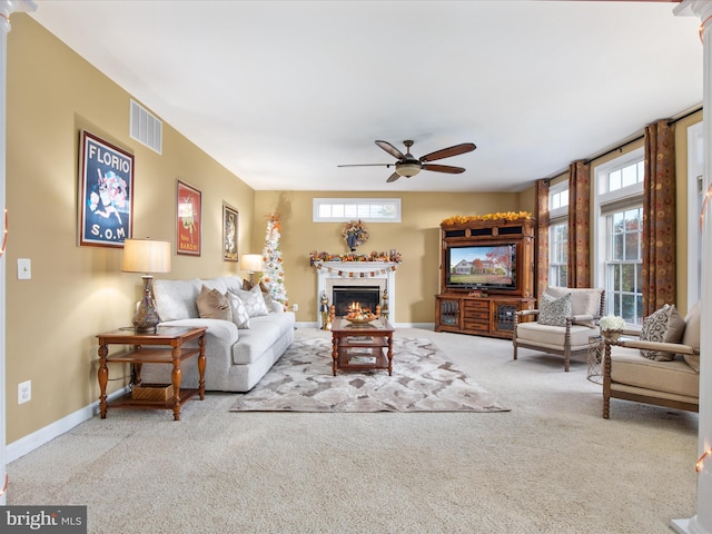 living room with a wealth of natural light, carpet floors, and ceiling fan