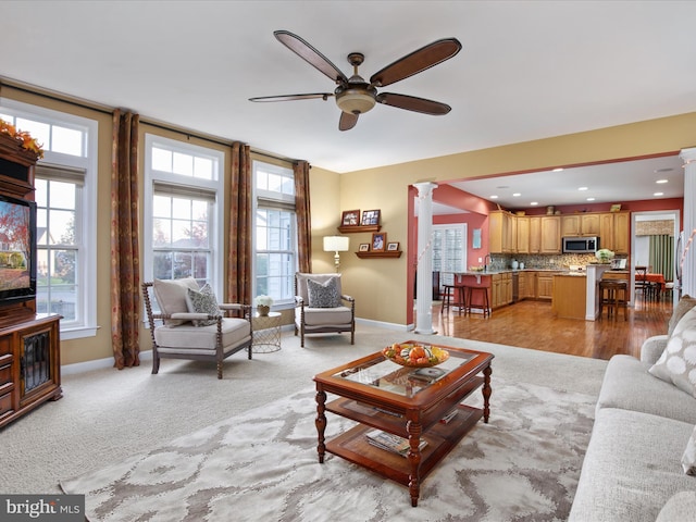 living room with ornate columns, light hardwood / wood-style flooring, ceiling fan, and sink