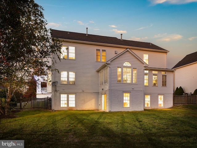 back house at dusk with a lawn