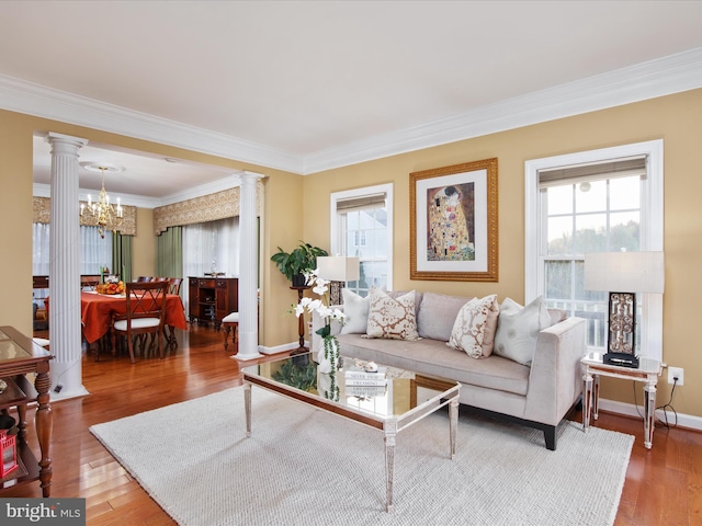 living room with a chandelier, wood-type flooring, ornate columns, and crown molding