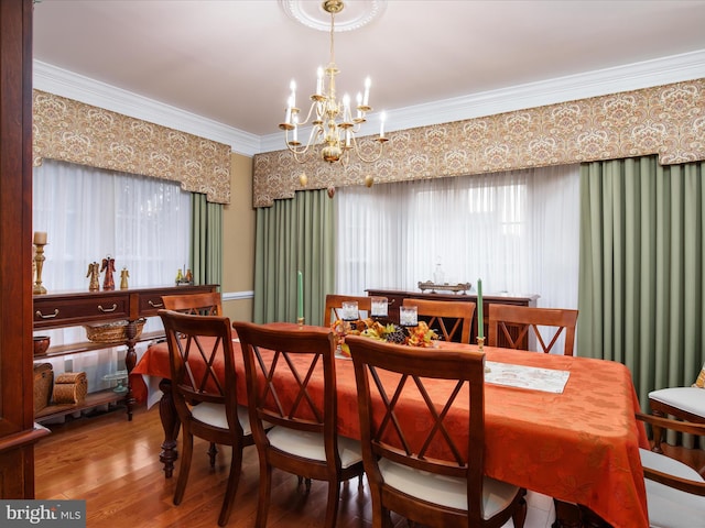 dining space featuring ornamental molding, hardwood / wood-style flooring, and a chandelier