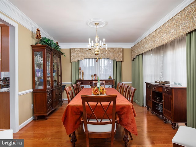 dining area with wood-type flooring, a chandelier, and crown molding