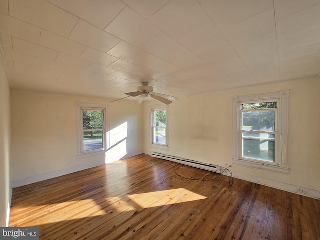 unfurnished room featuring a healthy amount of sunlight, wood-type flooring, and a baseboard heating unit