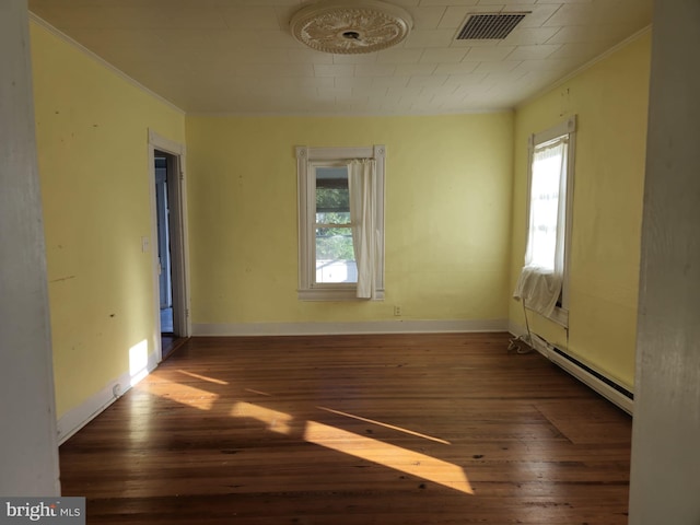 unfurnished room featuring a baseboard heating unit, a healthy amount of sunlight, and dark hardwood / wood-style flooring