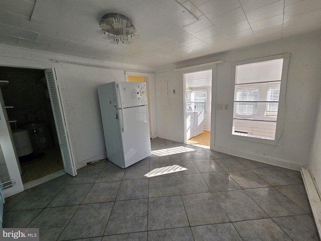 interior space with white fridge, tile patterned floors, and baseboard heating