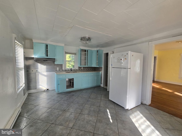 kitchen with backsplash, blue cabinetry, dark tile patterned flooring, white fridge, and sink