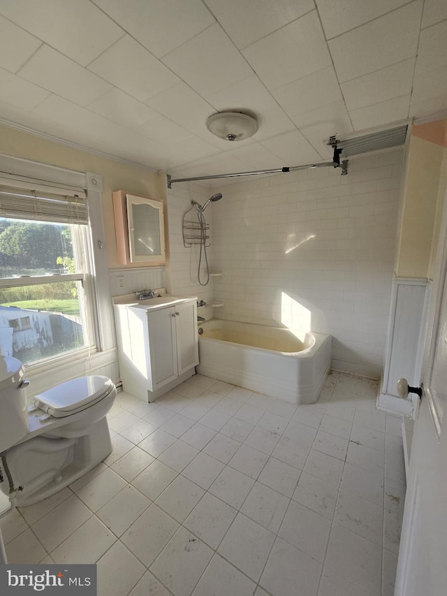 full bathroom with toilet, tile patterned floors, tile walls, tiled shower / bath, and vanity