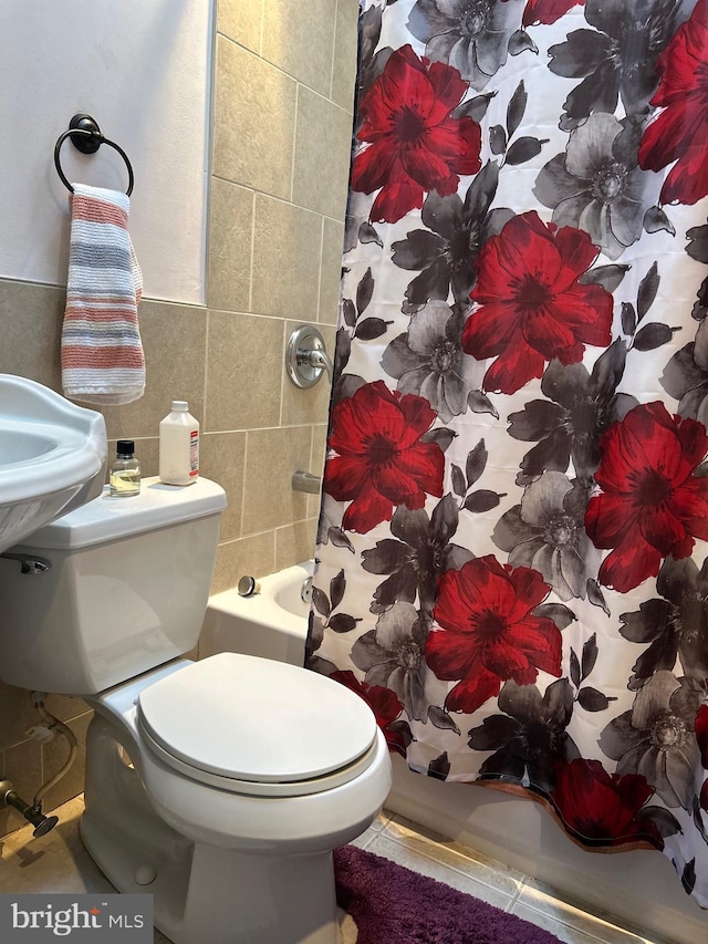 bathroom with toilet, shower / bathtub combination with curtain, and tile walls