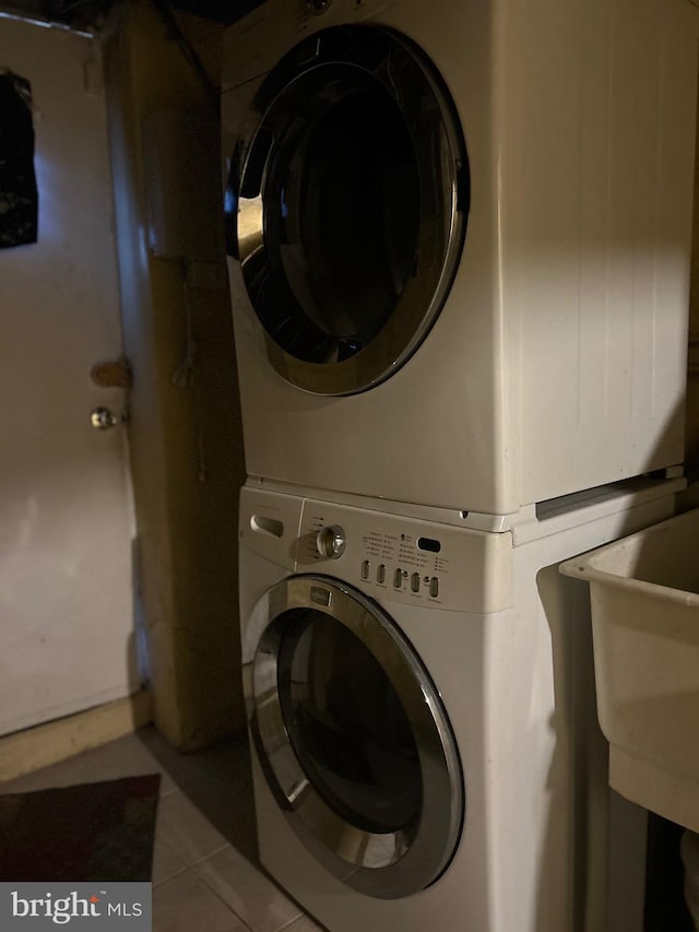 clothes washing area with light tile patterned floors and stacked washing maching and dryer