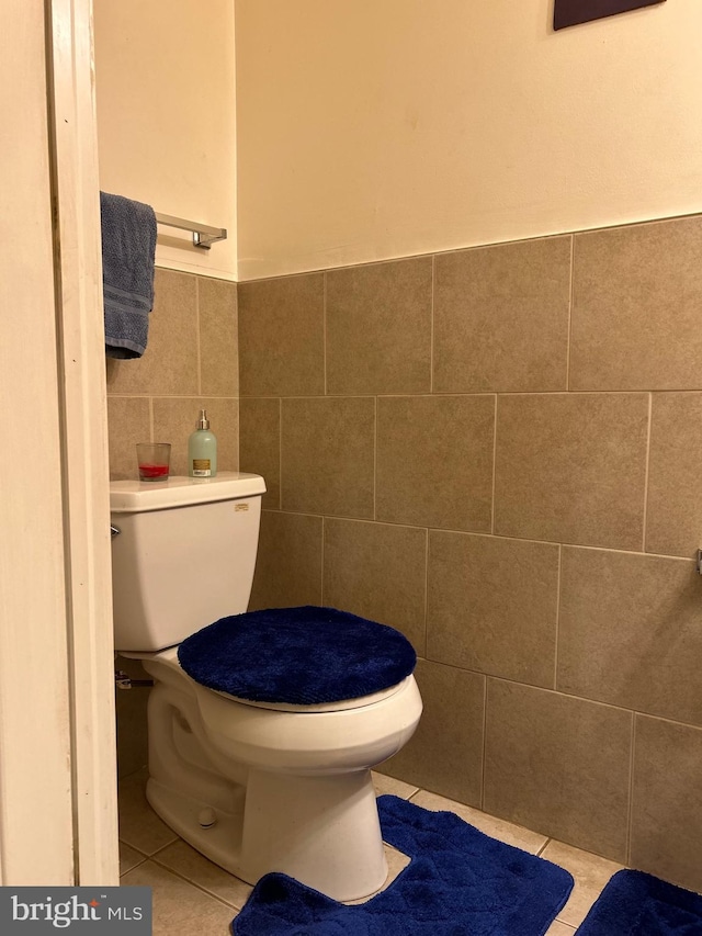 bathroom with toilet, tile patterned floors, and tile walls