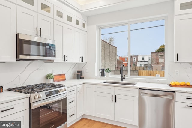 3011 Gaul St, Philadelphia, PA 19134 - kitchen with stainless steel appliances, a sink, white cabinets, decorative backsplash, and glass insert cabinets