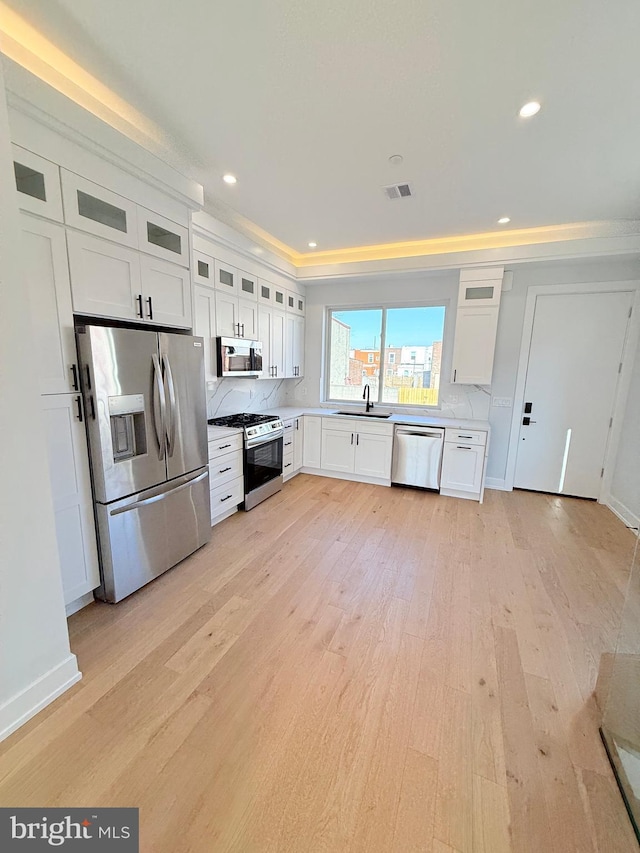 3011 Gaul St, Philadelphia, PA 19134 - kitchen featuring stainless steel appliances, a sink, light wood-style flooring, ornamental molding, and white cabinetry