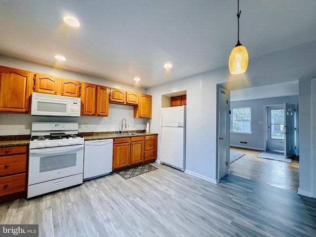 kitchen featuring sink, decorative light fixtures, white appliances, and light wood-type flooring