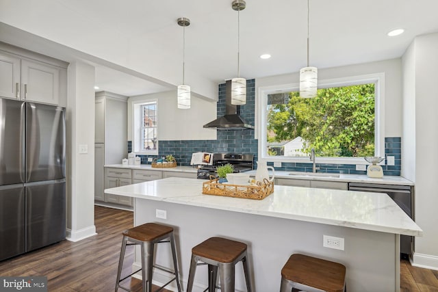 kitchen featuring appliances with stainless steel finishes, dark wood-type flooring, gray cabinetry, wall chimney exhaust hood, and sink