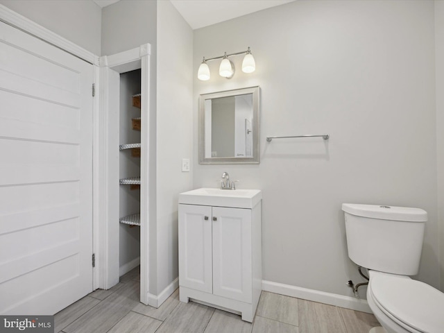 bathroom with toilet, vanity, and hardwood / wood-style floors