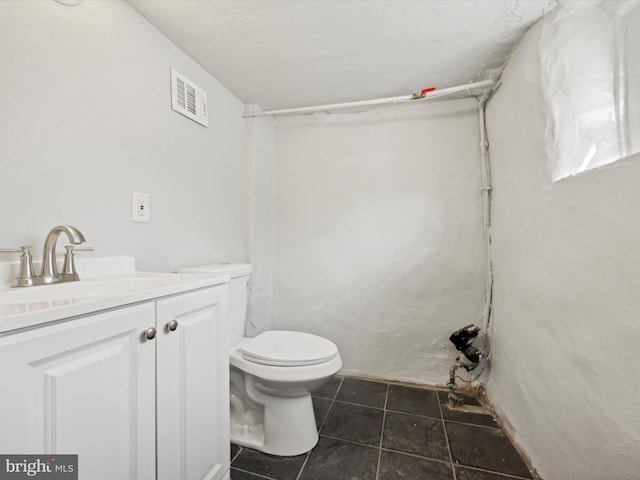 bathroom with toilet, vanity, and tile patterned floors