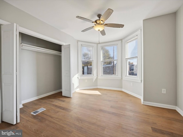 unfurnished bedroom with multiple windows, wood-type flooring, and ceiling fan