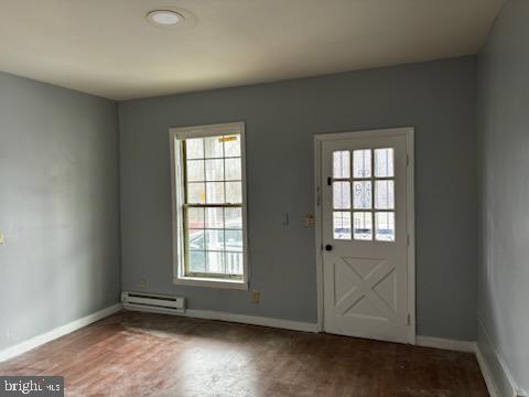 doorway to outside featuring a wealth of natural light, wood-type flooring, and baseboard heating