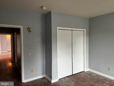 unfurnished bedroom with dark wood-type flooring and a closet