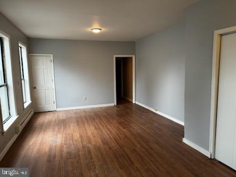 empty room featuring a baseboard radiator and dark hardwood / wood-style floors