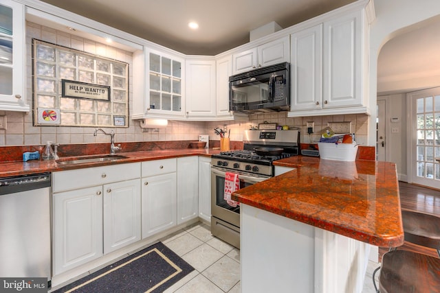 kitchen featuring light tile patterned flooring, appliances with stainless steel finishes, sink, and white cabinets