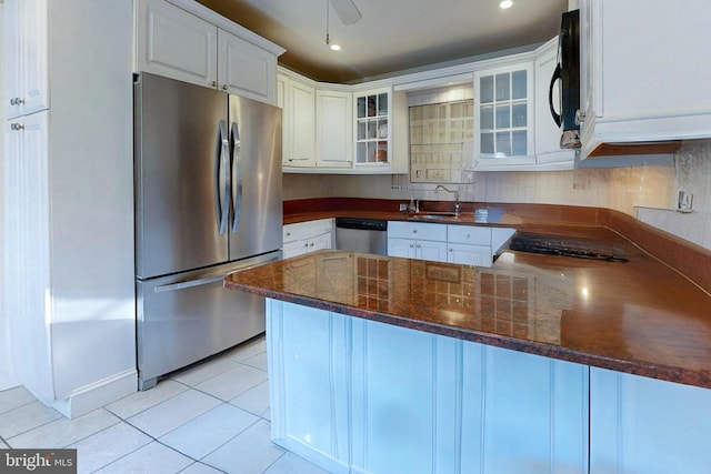 kitchen with kitchen peninsula, white cabinets, light tile patterned floors, appliances with stainless steel finishes, and sink