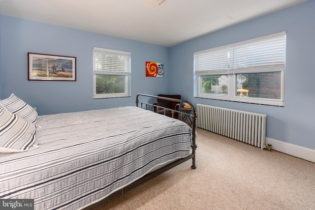 bedroom with radiator, multiple windows, and carpet floors