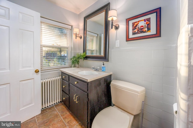 bathroom featuring vanity, toilet, tile walls, and radiator heating unit