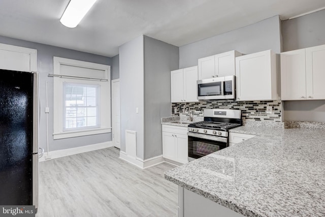 kitchen with white cabinets, light wood-style floors, and stainless steel appliances