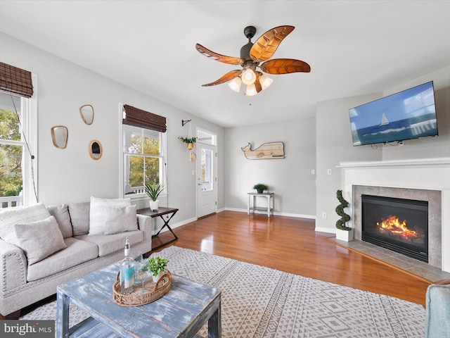 living room featuring a tile fireplace, wood-type flooring, a healthy amount of sunlight, and ceiling fan