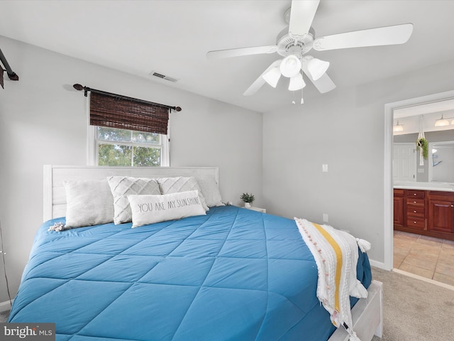 carpeted bedroom with ensuite bathroom and ceiling fan