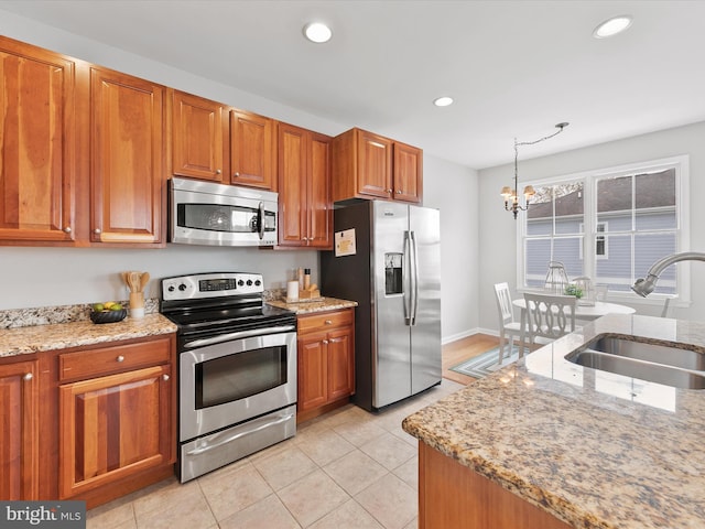 kitchen with light stone countertops, appliances with stainless steel finishes, sink, a notable chandelier, and light tile patterned floors